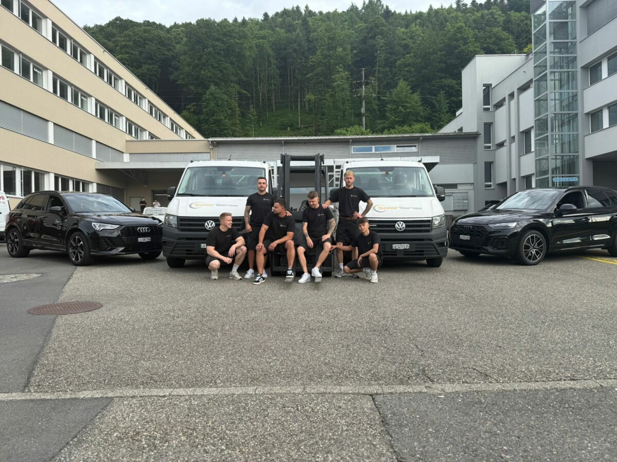 Das Montageteam von SolarSense mit Firmenfahrzeugen und Stapler vor dem Betriebsgebäude in Luzern.