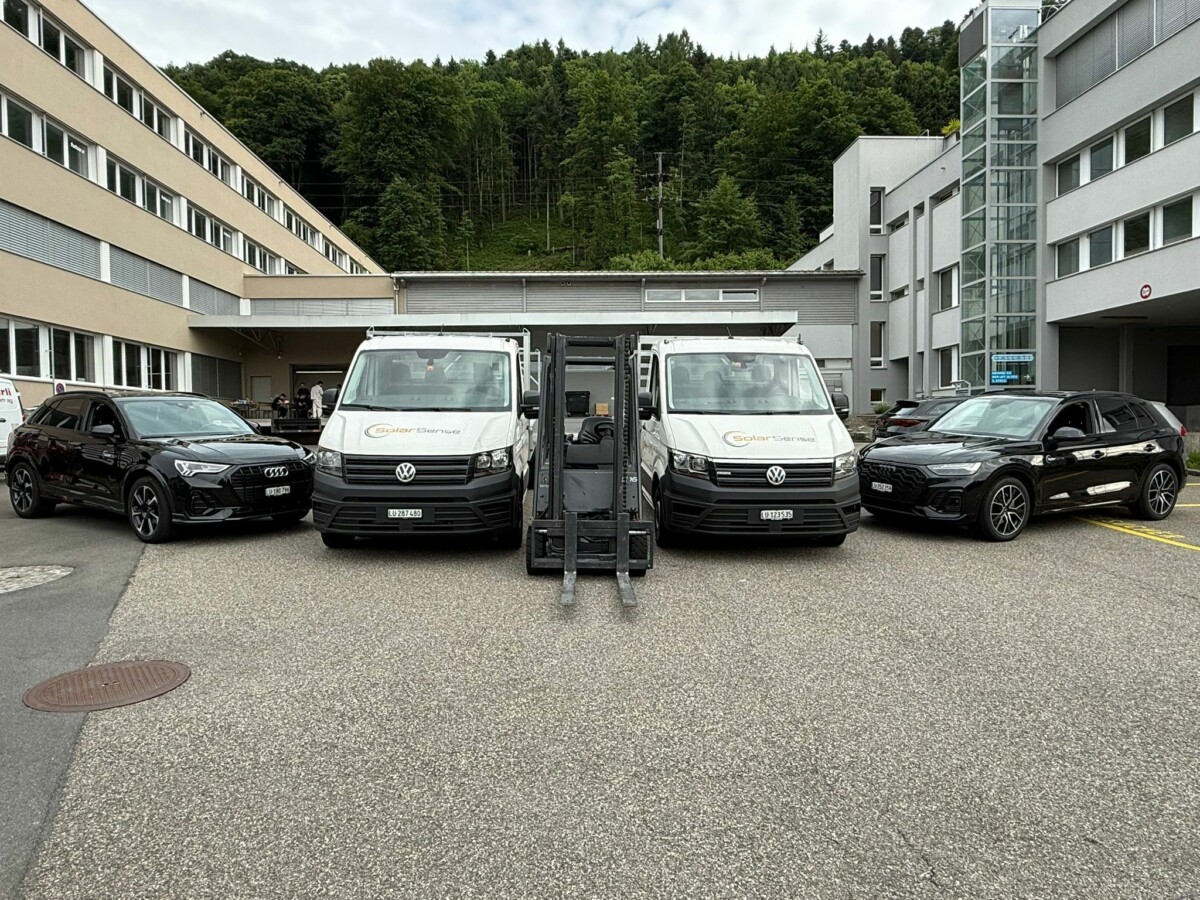 Zwei SolarSense-Montagefahrzeuge mit Stapler auf dem Firmenparkplatz in Luzern.