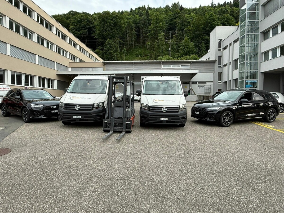 Fuhrpark von SolarSense: zwei Montagefahrzeuge und ein Gabelstapler vor dem Betriebsgebäude.